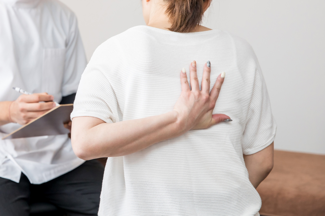 背中を抑える手